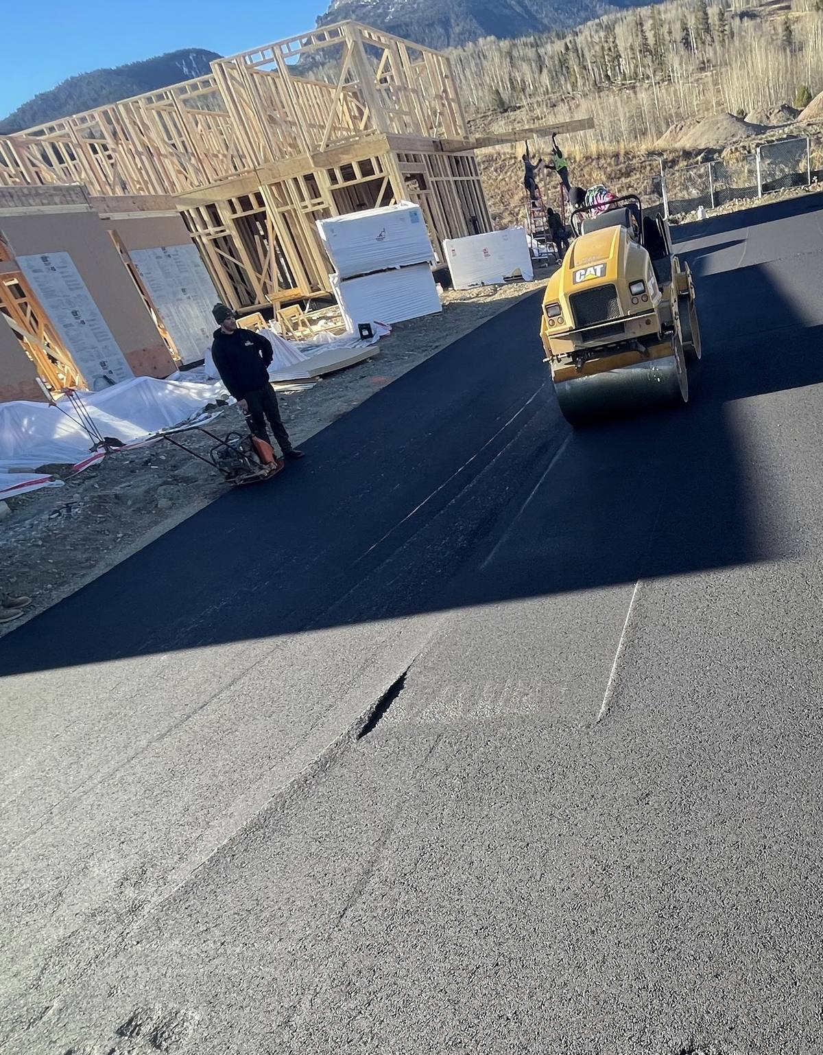 Rolling the new mat down a subdivision road with the houses still being framed.