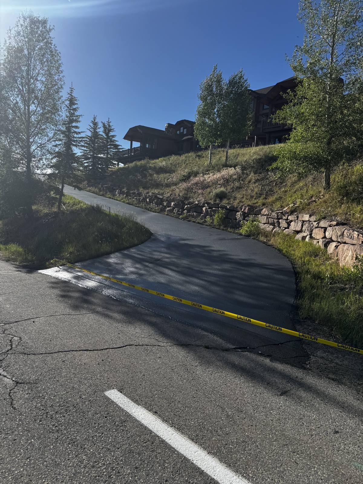 A new asphalt apron curving up from the road toward a hillside home