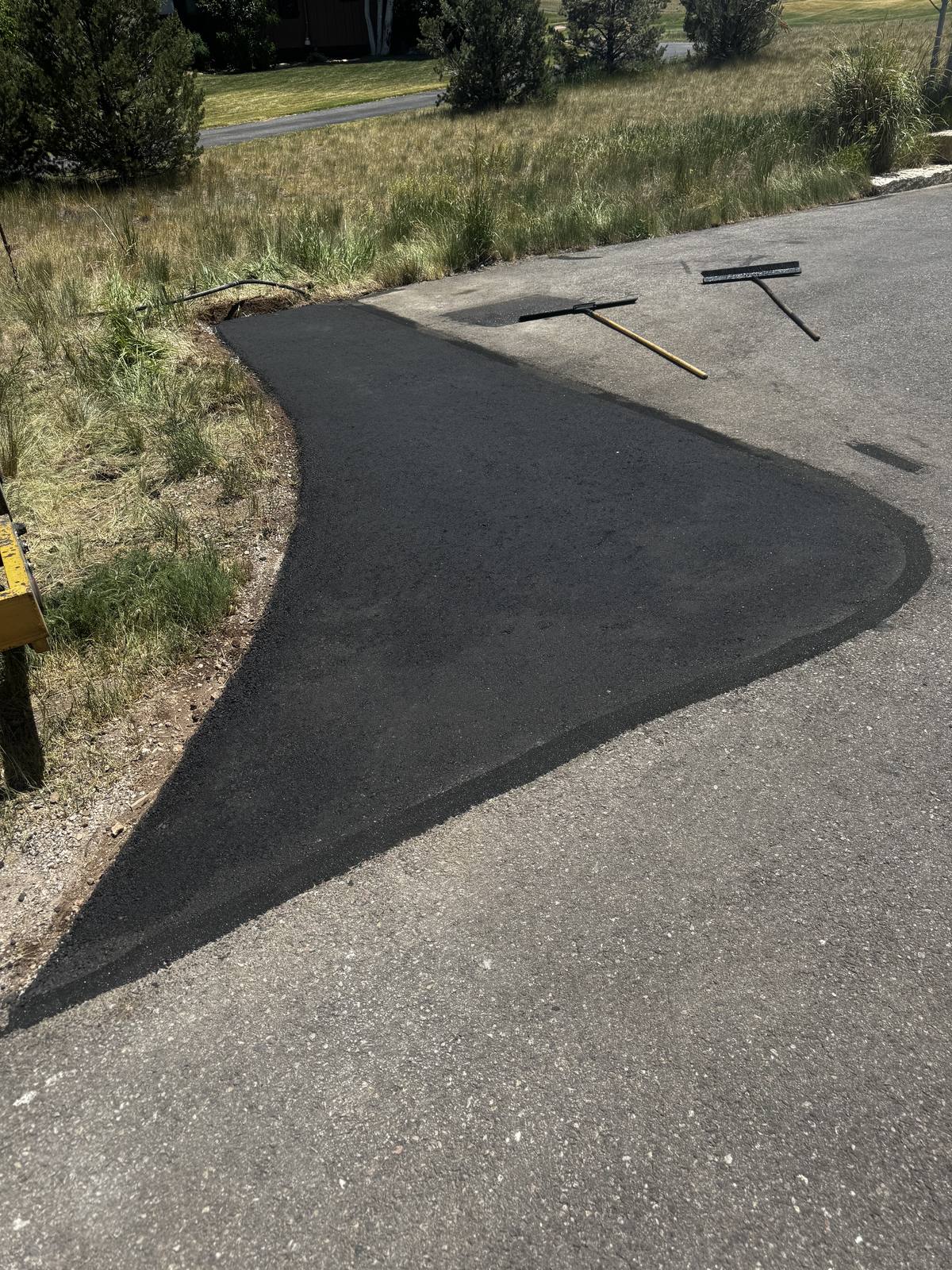 A patched section of new asphalt with the lute and screed still lying on the pavement
